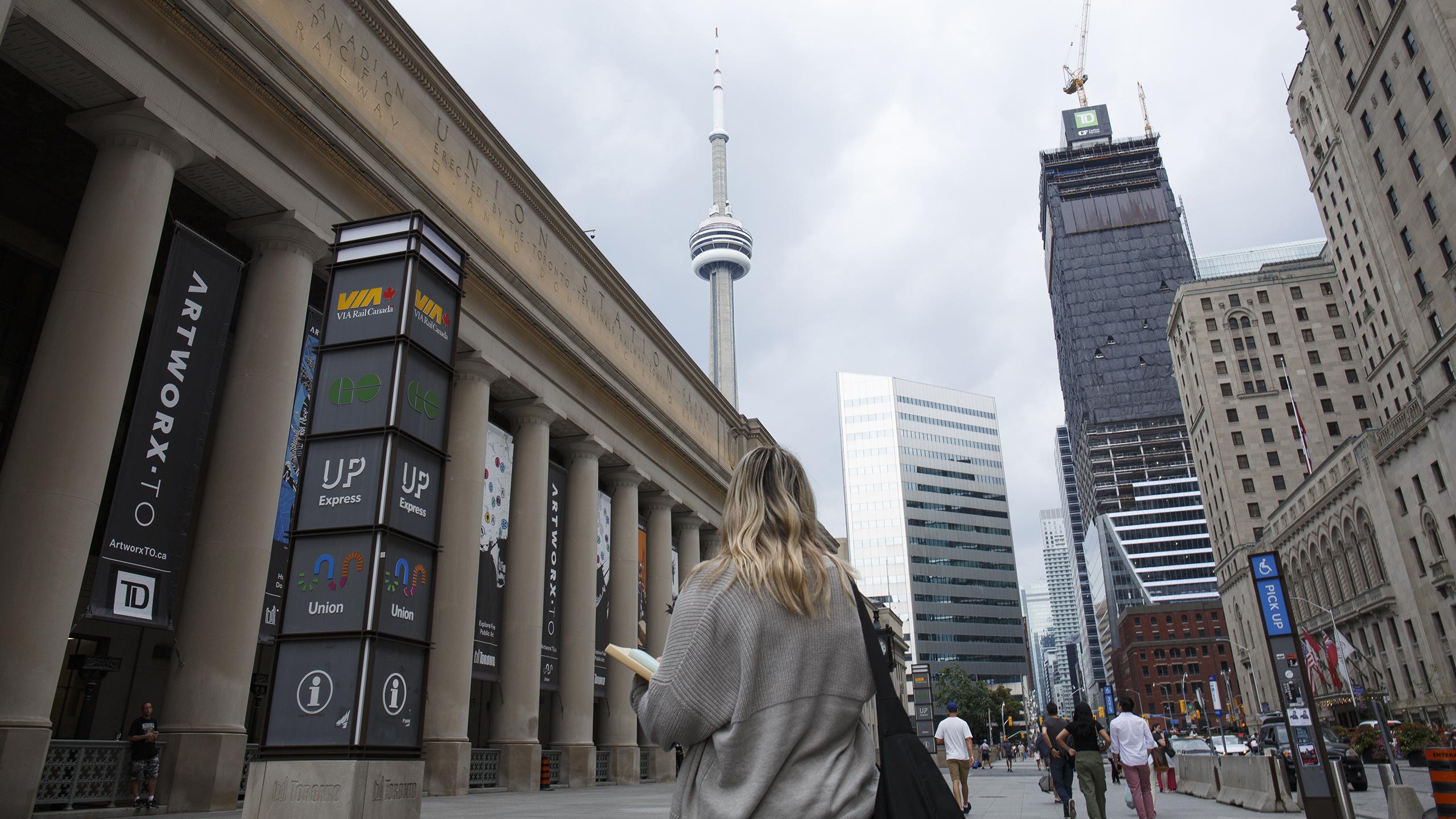 A student located out front of Union Statio staring up at the CN Tower