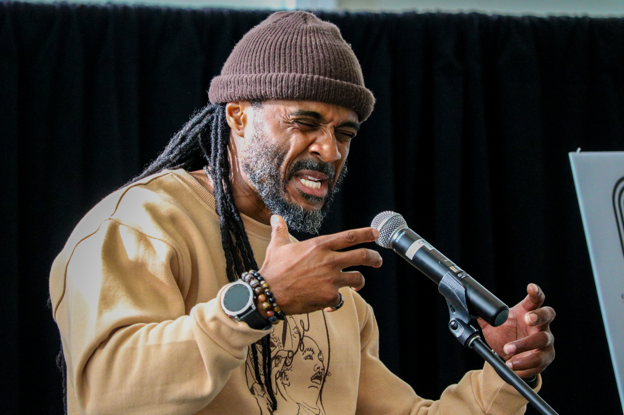 Nigel Birch Jr. speaks with a gritty face and his hands raised near a microphone