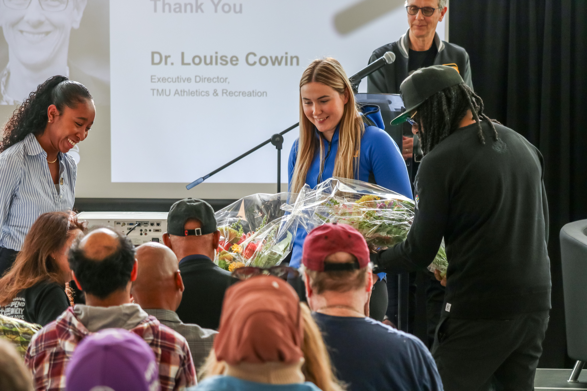 Haley Fedick helps hand out flowers to guests at TMU'd John Carlos event
