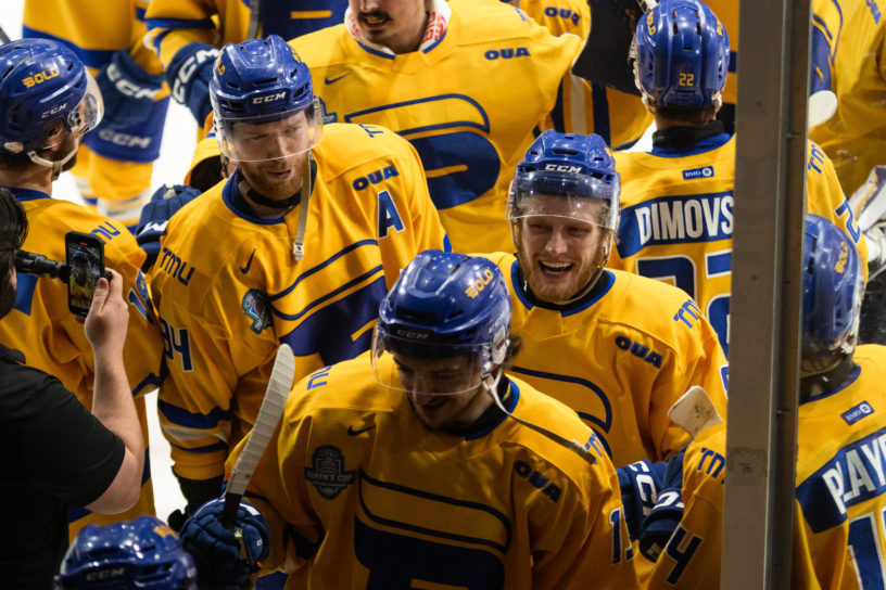 The TMU Bold gather on the ice next to the glass